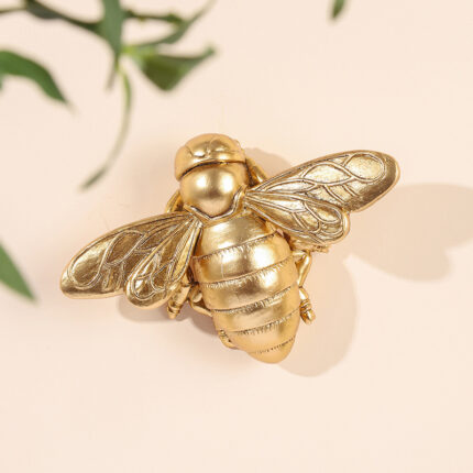 Golden 3D metallic bee wall sculpture with detailed wing veins on light background