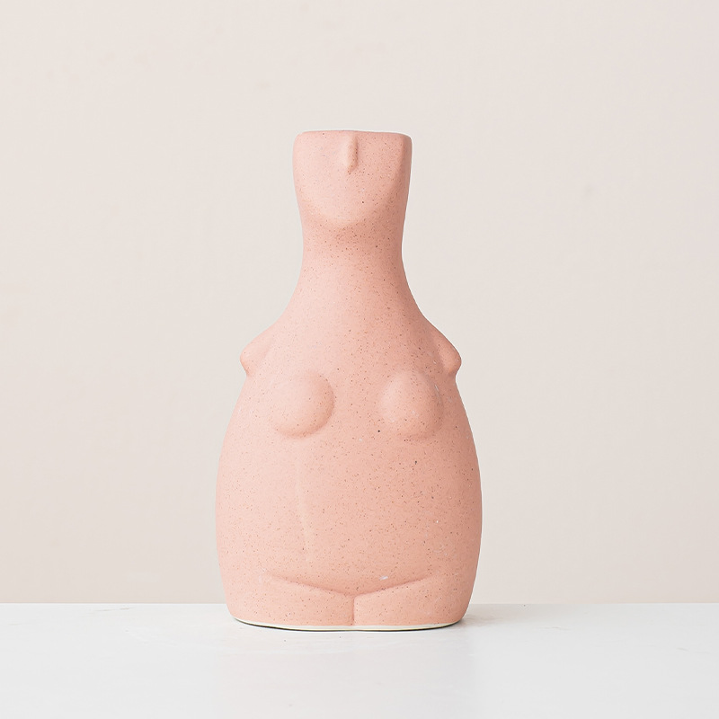 Minimalist pale pink abstract female body vase with speckled texture, isolated on beige background