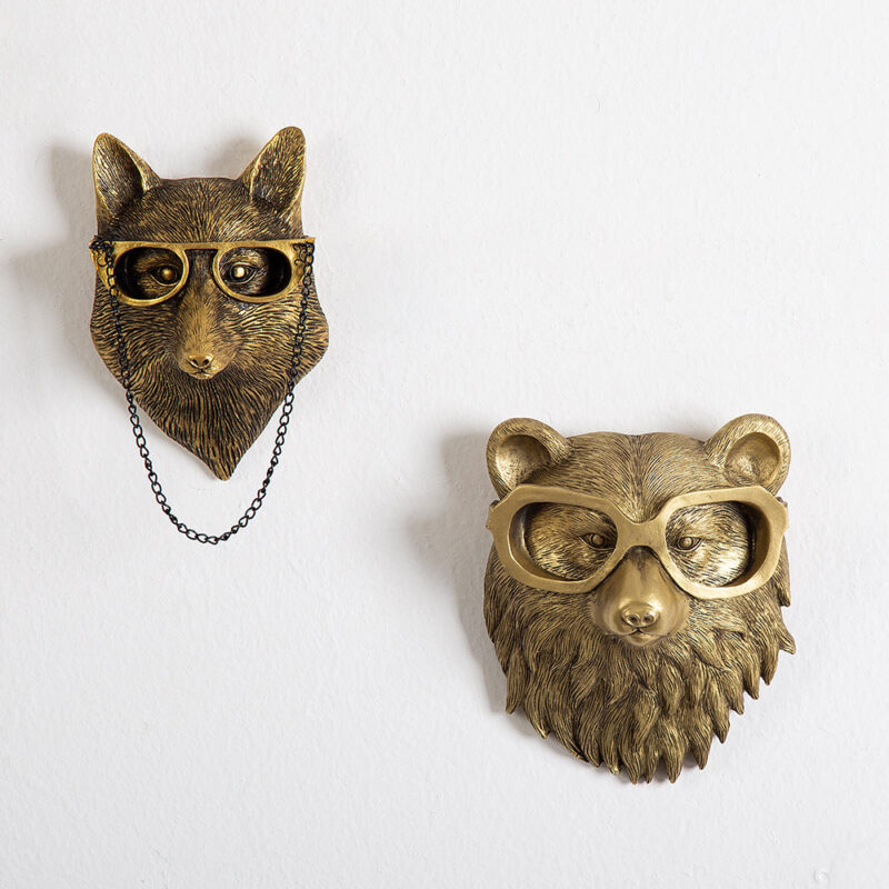 Pair of gold animal head wall sculptures (fox/bear) with glasses & chains on pure white wall | Vintage-inspired faux taxidermy art with textured fur details