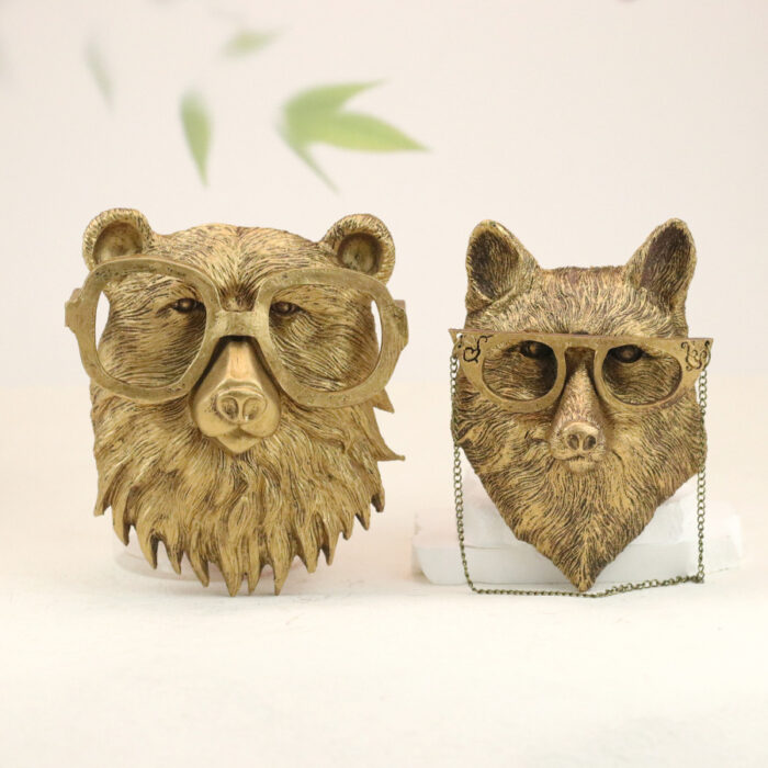 Gold bear & wolf head wall decor pair with retro glasses, wolf with chain accents on muted green foliage backdrop | Whimsical faux taxidermy art for modern interiors