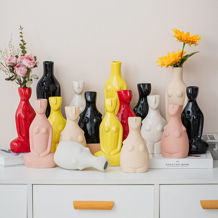 Modern sculptural body vase decor in abstract human forms with flowers, displayed on white cabinet
