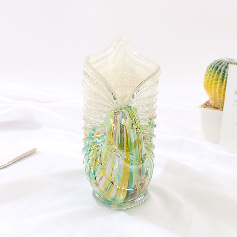 Organic-shaped decorative glass vase with wavy rim and multi-color stripes in green, yellow, blue, styled with gradient-hued cactus on white fabric backdrop.