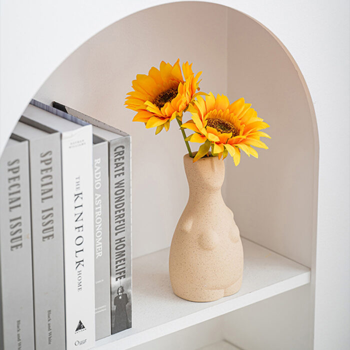 Beige sculptural bust vase with sunflowers in arched niche, styled with magazines