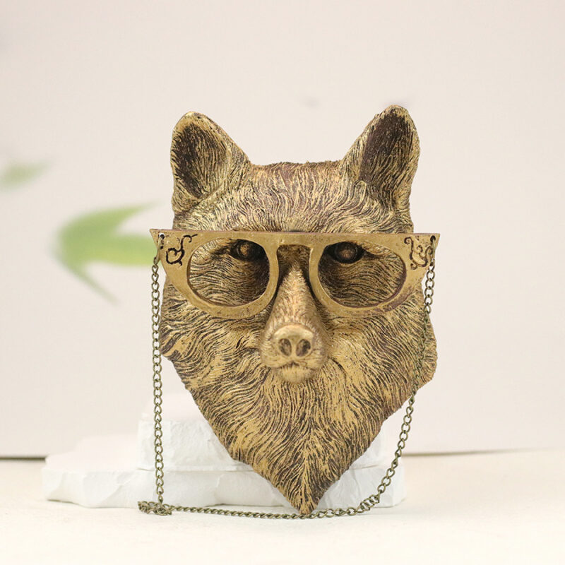 Bronze fox head wall sculpture with steampunk glasses & chains, textured fur details on sage green botanical backdrop | Whimsical faux taxidermy wall art for industrial interiors