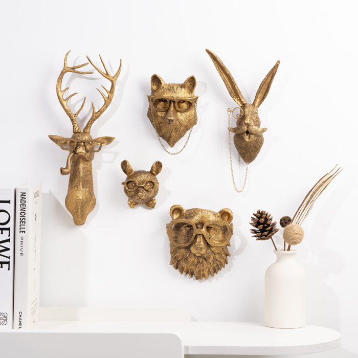 Gold animal head wall decor set (deer/fox/rabbit/bear) with glasses & monocle chains, mounted on white wall with books and dried pinecone vase | Chic faux taxidermy wall art for luxury interiors
