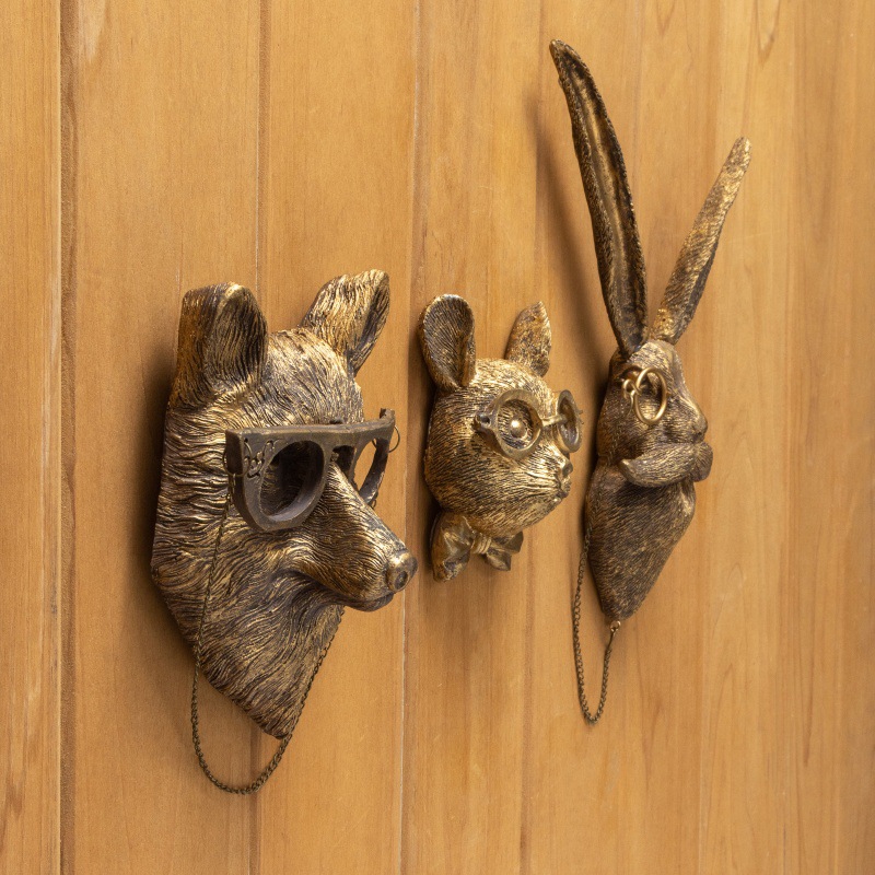 Modern bronze animal head wall decor set (fox/mouse/rabbit) with glasses & bow tie, hanging via chains on light wood panel wall | Vintage-inspired metal wall sculptures for contemporary interiors