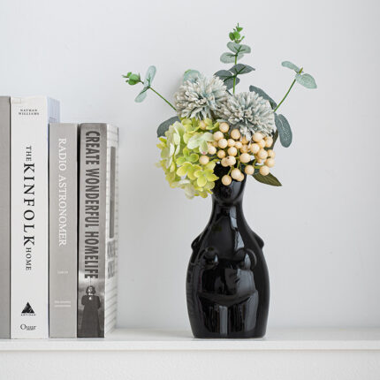 Black sculptural body vase with hydrangeas, chrysanthemums and eucalyptus on white desk