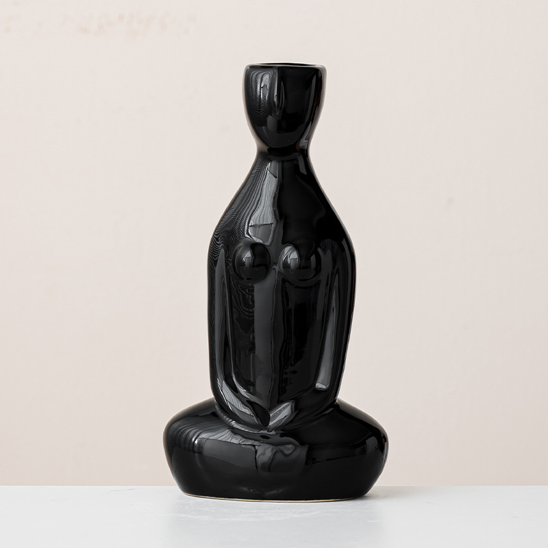 Glossy black female body sculpture vase with seated base, abstract facial contours on neutral background